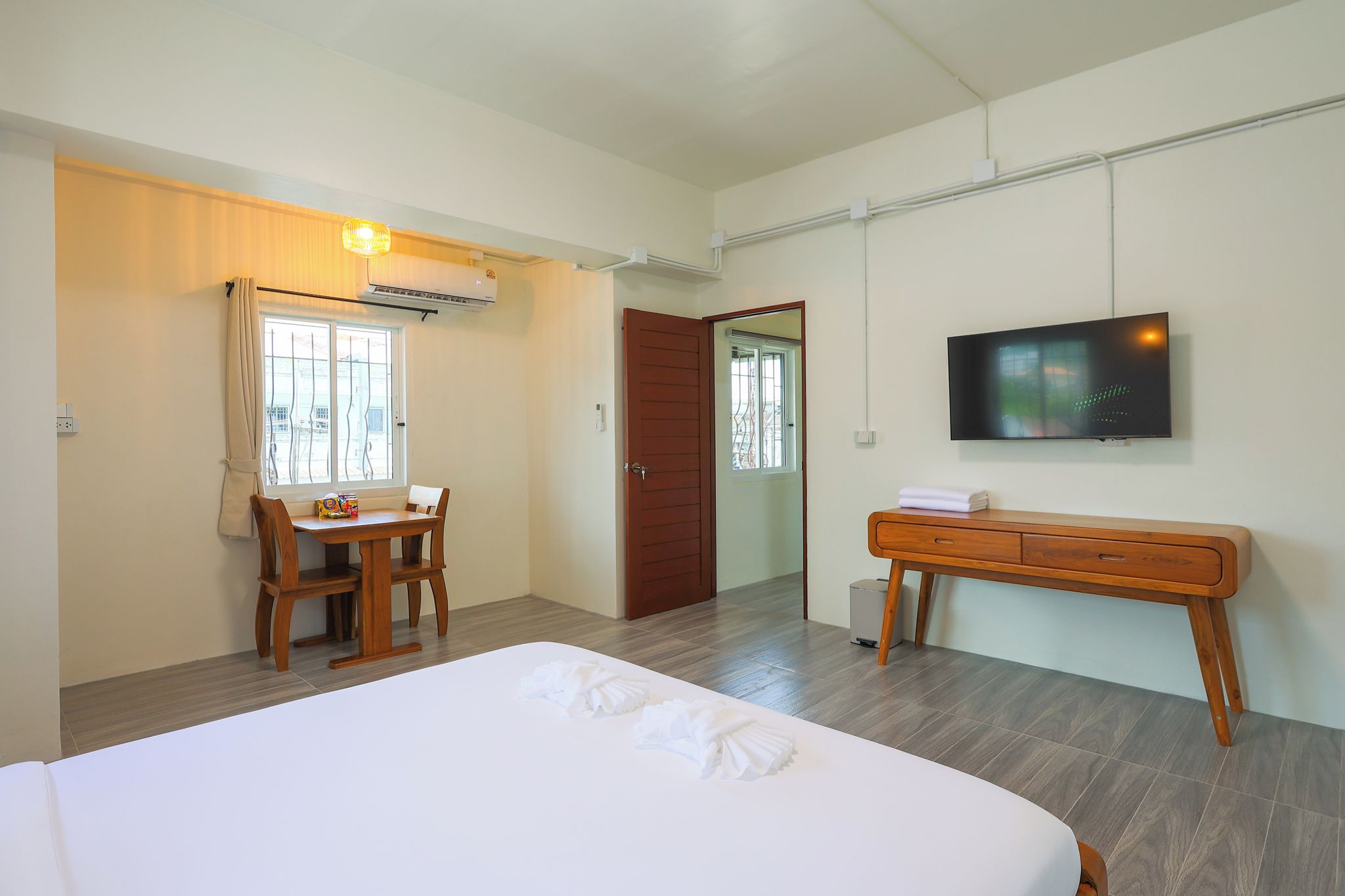 A hotel room with a bed, a desk, a chair, a television, and a wardrobe.
