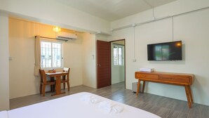 Ein Hotelzimmer mit einem Bett, einem Schreibtisch, einem Sessel, einem Fernseher und einem Kleiderschrank.