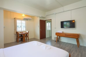 Een hotelkamer met een bed, bureau, stoel, televisie en garderobe.