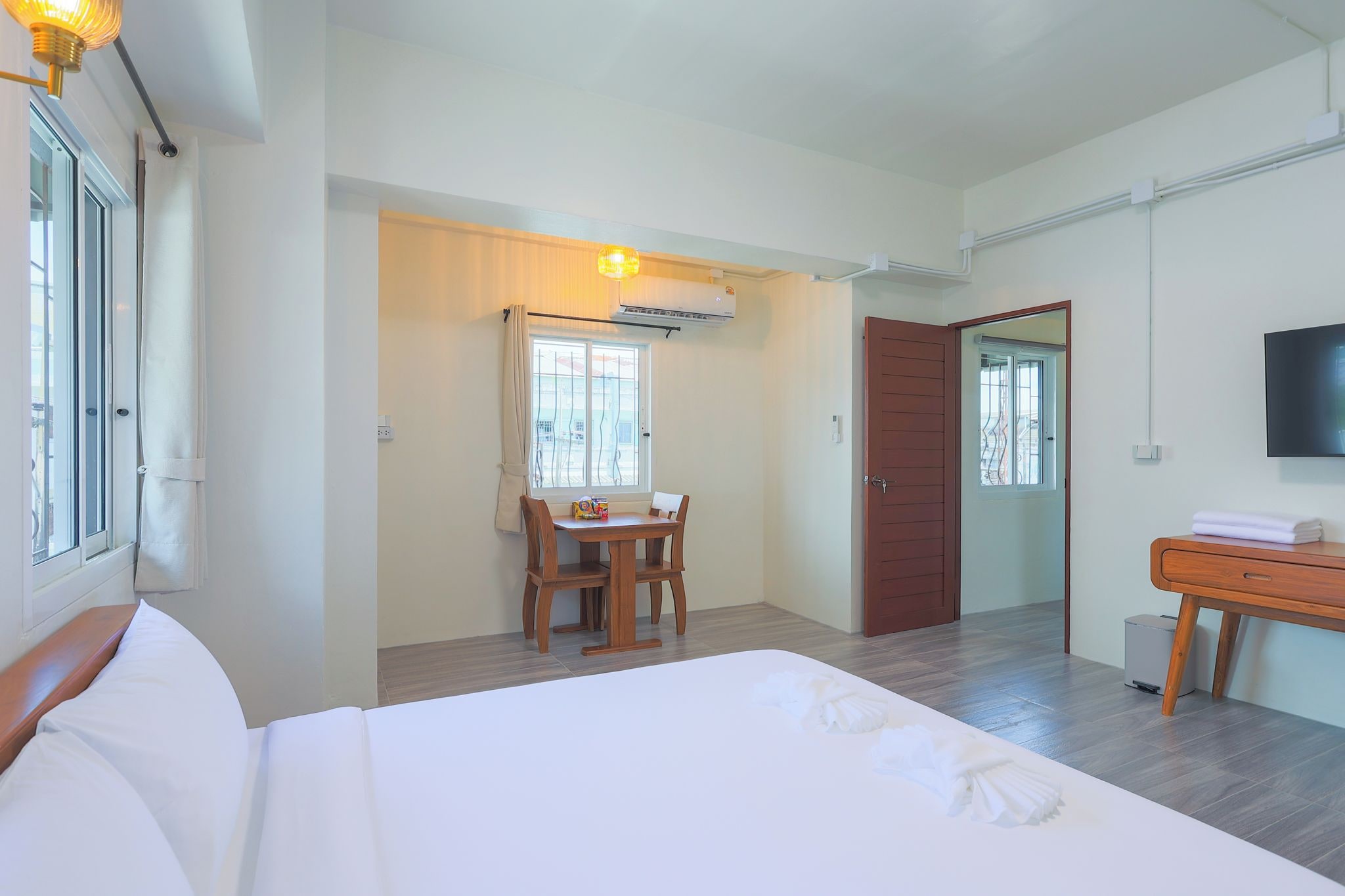 A hotel room with a bed, a desk, a chair, a television, and an air conditioning unit.