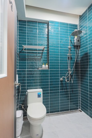 Een badkamer met toilet, een douche met handdouche en een plank met toiletartikelen.