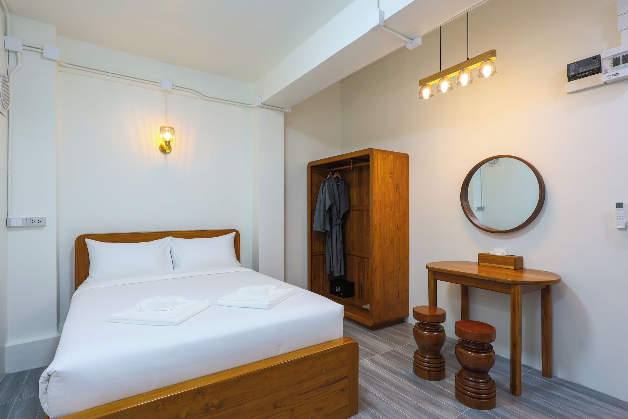 Ein Hotelzimmer mit einem Bett, einem Holzschrank, einem runden Spiegel und einem kleinen Holztisch.