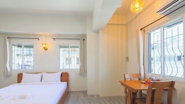 Ein Hotelzimmer mit einem Bett, einem Esstisch mit Stühlen und einem Fenster mit Vorhängen.