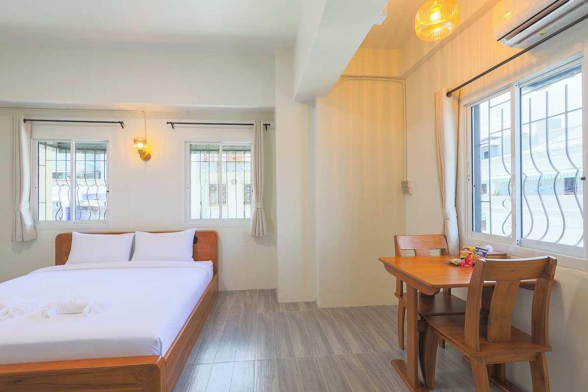 Een hotelkamer met een bed, een eettafel met stoelen en een raam met gordijnen.