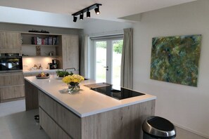 Eine moderne Küche mit Kochinsel, integrierten Geräten und Blick ins Freie.