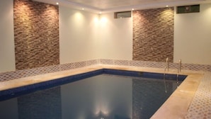 Una piscina con pared de piedra y borde de azulejos.