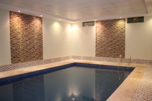 Una piscina con pared de piedra y borde de azulejos.