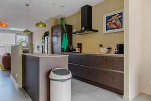 A modern kitchen with a central island, built-in appliances, and a large window. - Lovely house in Zoutelande for 8 persons - Duinweg 11 (Zoutelande)