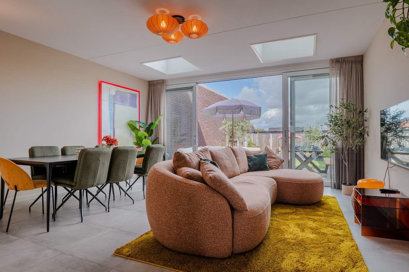 A modern living room with a sectional sofa, dining table, chairs, and a TV.