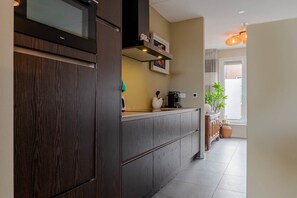 Una cocina moderna con armarios de madera oscura, microondas integrado y una cafetera sobre la encimera.
