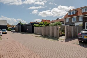 A residential street with houses, a garage, and parked cars. - Lovely house in Zoutelande for 8 persons - Duinweg 11 (Zoutelande)