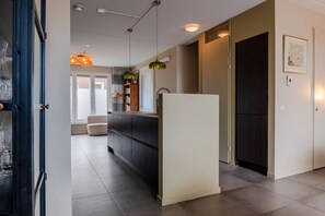 A modern kitchen with a central island, a refrigerator, and a dining area with a chair. - Lovely house in Zoutelande for 8 persons - Duinweg 11 (Zoutelande)