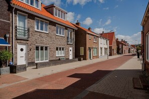 A street with brick buildings, some with balconies and windows, and a clear sky. - Lovely house in Zoutelande for 8 persons - Duinweg 11 (Zoutelande)