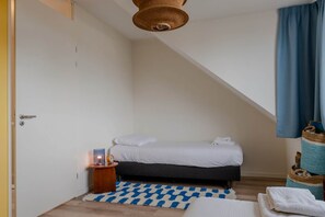 A small, cozy bedroom with a bed, bedside table, and a hanging light fixture. - Lovely house in Zoutelande for 8 persons - Duinweg 11 (Zoutelande)