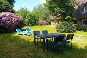 Ein Garten mit Tisch und Stühlen, einer Rasenfläche und einem Haus im Hintergrund.
