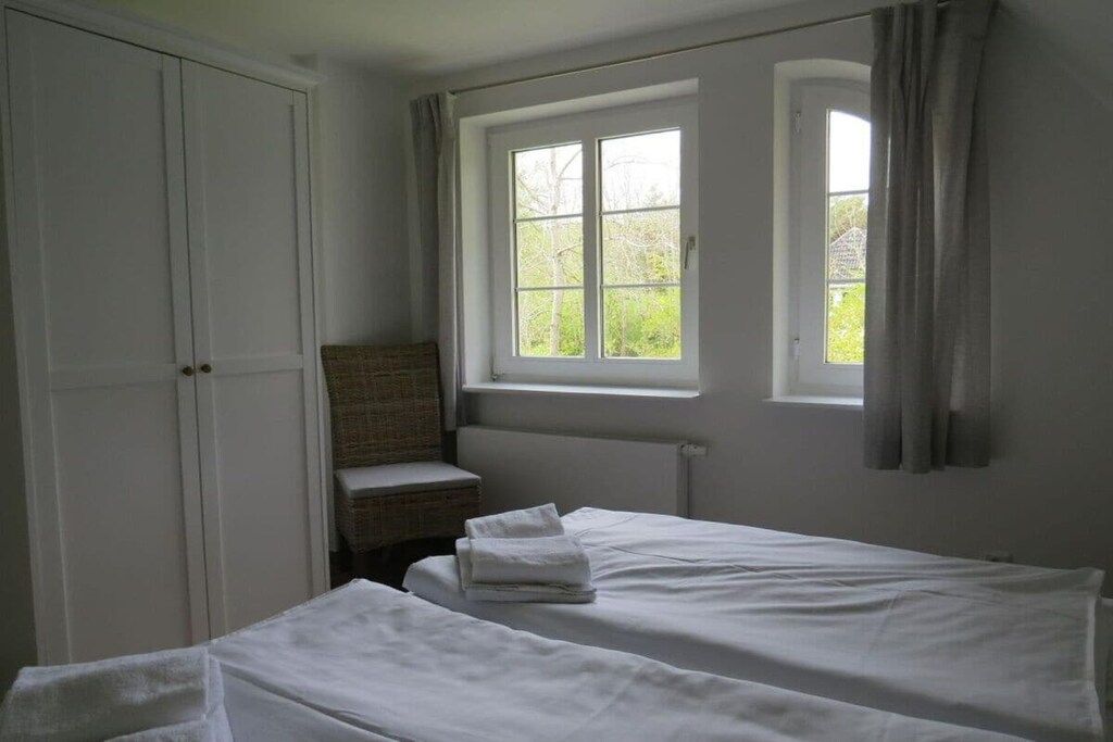 Une chambre avec deux lits, une fenêtre avec des rideaux, un radiateur et une armoire.