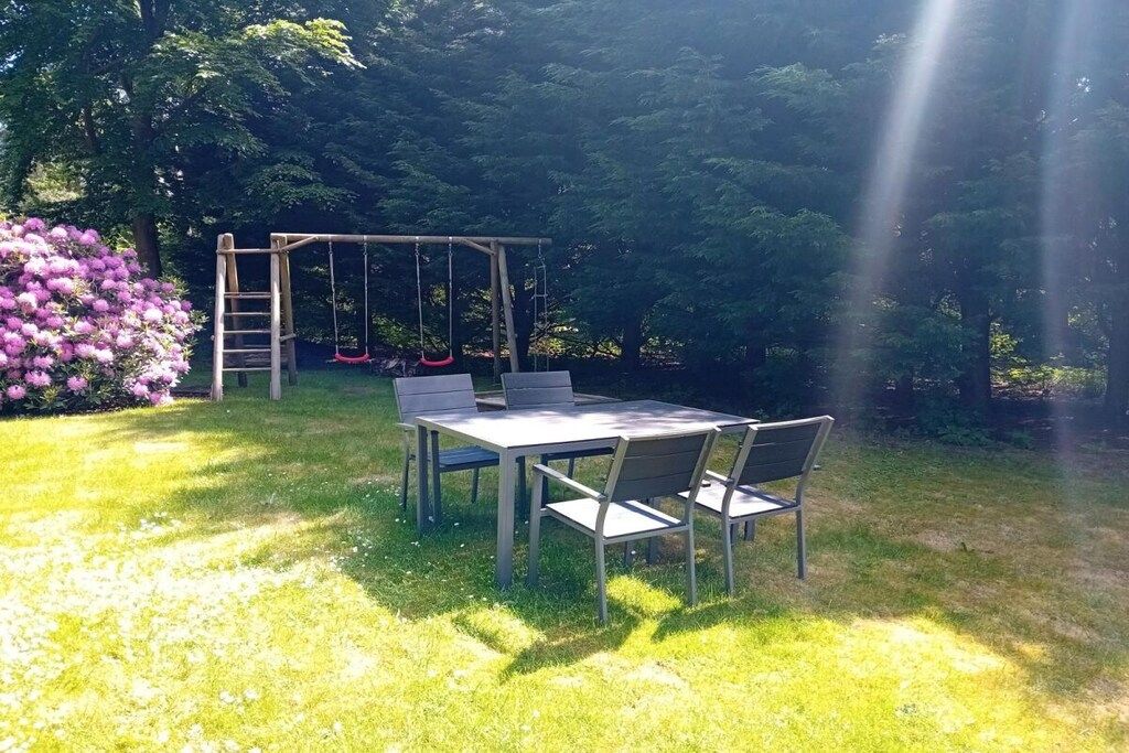 A garden with a swing set, a table with chairs, and a bench.
