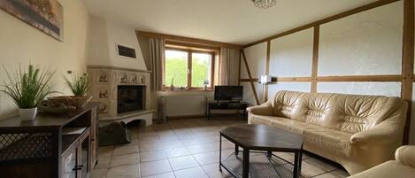 Una sala de estar con chimenea, televisor, sofá y mesa de centro.