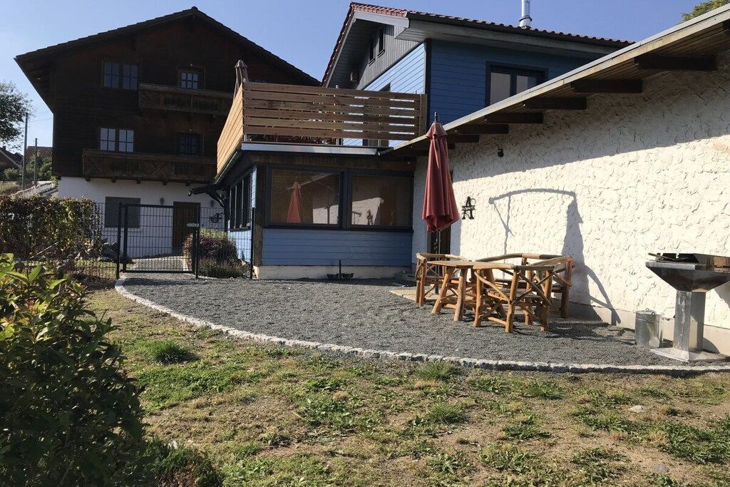 Un edificio de dos plantas con una terraza de madera y una parrilla.