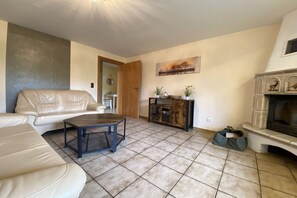A living room with a sofa, coffee table, fireplace, and a painting on the wall. - Holiday home in Stiege with barbecue (Stiege)