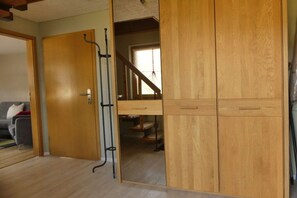 Ein Zimmer mit einem Holzschrank, einer Tür zu einem anderen Raum und einer Treppe.