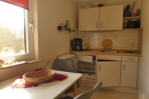 A compact kitchen with a window, a coffee maker, a sink, and cabinets. - Holiday apartment in Wieck with swimming pool (Wieck)