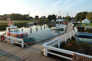 A dock with boats, a white fence, and a grassy area in the background. - Holiday apartment in Wieck with swimming pool (Wieck)