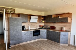 Eine moderne Küche mit grauen Schränken, einer Holz Arbeitsplatte und einem eingebauten Backofen.