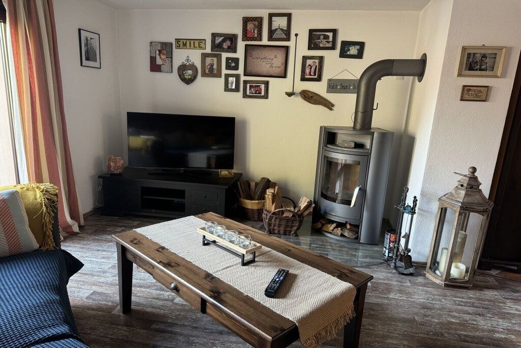 A living room with a television, a fireplace, and a coffee table with glasses.