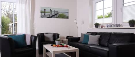 Una sala de estar moderna con un sofá, sillones, una mesa de centro y un cuadro en la pared.