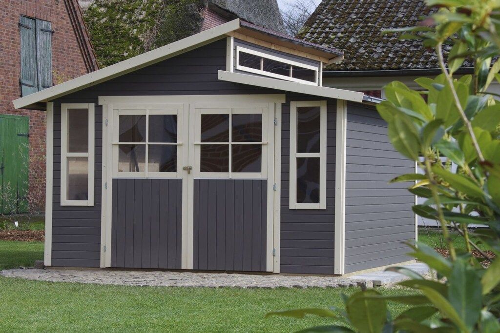A small, single-story shed with a dark exterior and white trim, featuring two large doors and multiple windows.