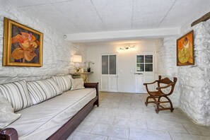 A room with a sofa, a chair, a door, and two paintings on the walls.
