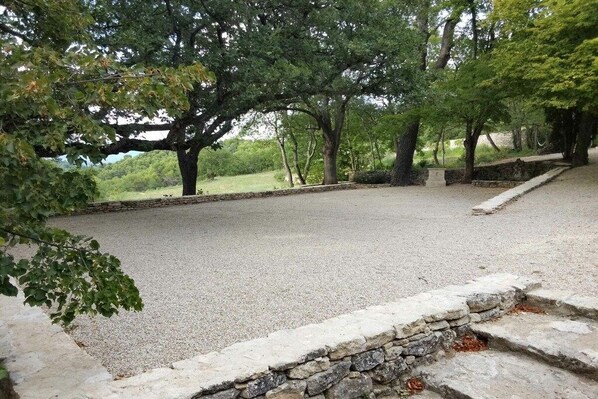 A gravel area with stone steps and trees, likely a park or outdoor seating area.