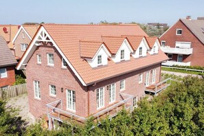 Ein Wohngebäude mit roten Ziegeln, mehreren Fenstern und einem Balkon.