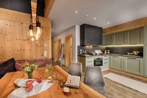 A modern kitchen with wooden cabinets, a dining area with a wooden table, and a built-in oven. - Holiday home in Stumm with barbecue (Stumm)