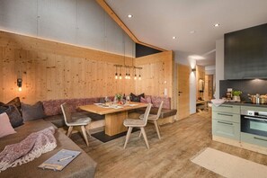 A modern interior with a wooden wall, a dining area with a table and chairs, and a kitchen with a stove. - Holiday home in Stumm with barbecue (Stumm)