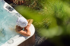 A person relaxing in a hot tub with a towel on their head, surrounded by greenery. - Holiday home in Stumm with barbecue (Stumm)