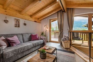 A cozy living room with a sofa, a coffee table, and a view of the outdoors through a large window. - Holiday home in Stumm with barbecue (Stumm)