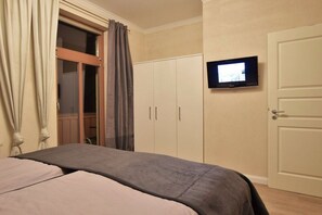 A bedroom with a bed, a television mounted on the wall, and a wardrobe. - Villa Käthe "Apartment - 6b" (Kühlungsborn)