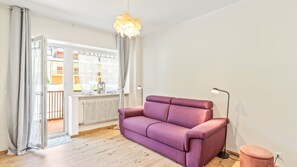 A living room with a sofa, a lamp, and a view through a window. - Nevea Lux with Sauna & Kanin View (Sella Nevea)