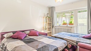 A bedroom with a bed, a bedside table, a window with curtains, and a radiator. - Nevea Lux with Sauna & Kanin View (Sella Nevea)