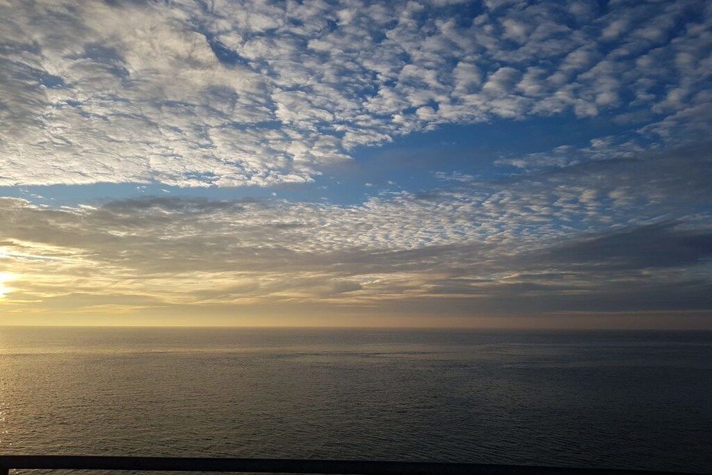 A view of the ocean with a horizon line and a cloudy sky.