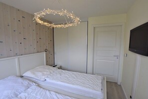 A bedroom with a bed, a wardrobe, a television, and a unique ceiling light fixture. - Holiday apartment with 2 bedrooms (Rantum)