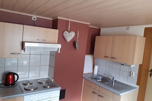 A compact kitchen with a gas stove, a sink, and wooden cabinets. - Holiday apartment in Jabel with swimming pool (Jabel)