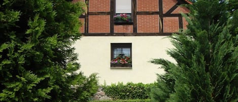 Une maison traditionnelle à colombages, avec une façade blanche et un toit à deux versants.