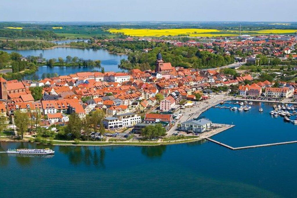 A town with red-roofed buildings, a marina, and a river.
