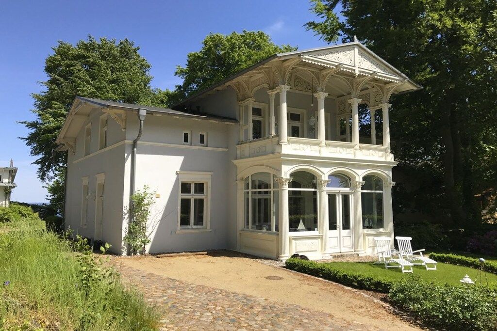 A white building with a covered porch and a garden.