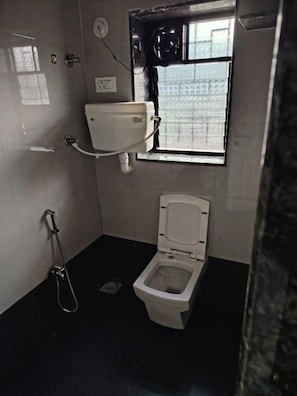 Un baño pequeño con inodoro, ducha y ventana.