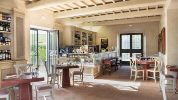 A spacious kitchen with a large island, open shelving with bottles, and a view through the glass doors.