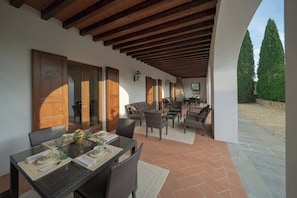 Un patio exterior con una mesa para dos, rodeado de mobiliario de mimbre.